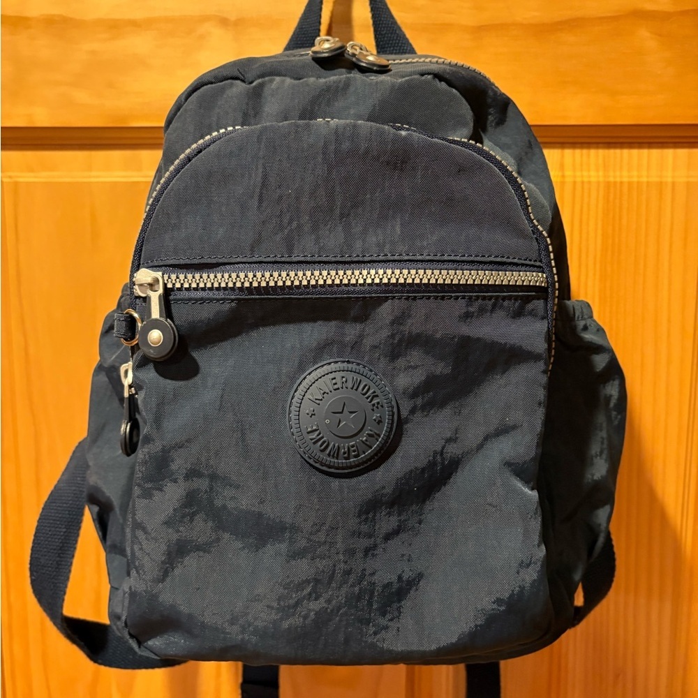 "Kaierwoke" backpack with silver zippers and a circular logo on the front